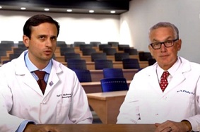 Drs. Malhotra and O'Malley sit together at a table wearing their white coats