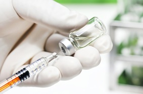 a needle going into a vial of a vaccine