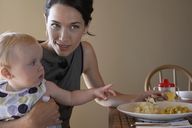 Woman eating next to baby