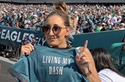 Andy Sealy posing with her Eagles jersey at a football game. 