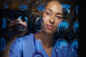 a female doctor or surgeon is analyzing the digitally generated scans of a human brain