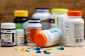 Various pills on a table in front of eight supplement bottles