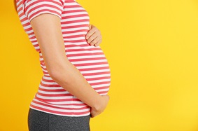 Pregnant woman wearing a striped shirt and holding her belly 