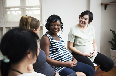 Four pregnant people talk while sitting in a circle.