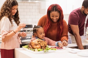 A mother, father and two children preparing a holiday turkey in their kitchen