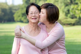 Daughter hugging mother, both wearing pink shirts