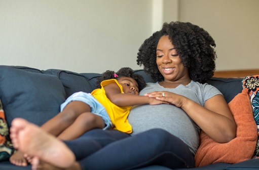 Toddler hugging pregnant mother while sitting on the couch