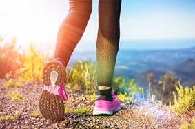 Woman's legs and feet shown walking on a mountain path