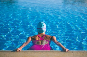 Female swimmer in pink bathing suit getting ready to start workout 