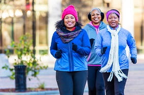 Three middle-aged African-American women walking outside in winter. 