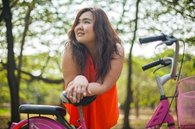 Young woman leaning on the seat of her bicycle while thinking