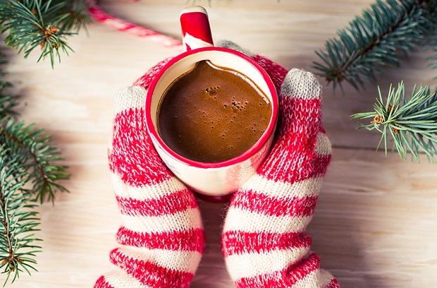 Gloved hands holding a mug of hot chocolate