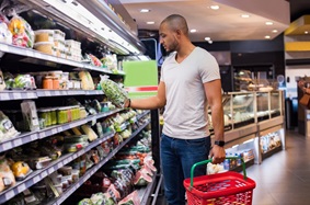 man looking at bag a of lettuce in a grocery store
