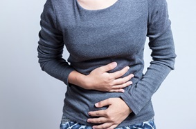 woman holding stomach, seemingly in pain