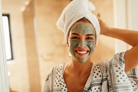 Smiling woman wearing a green beauty mask.