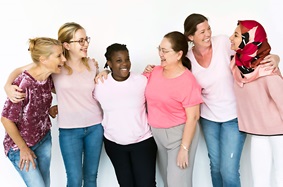 Women of varying ages and ethnicity smiling in a group 