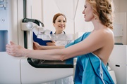 Patient receiving mammogram as technician looks on