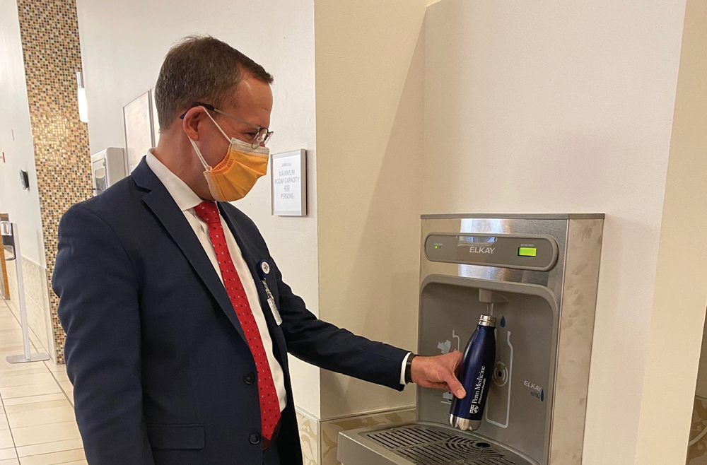 CEO James Demetriades using a touchless filtered water station installed at Princeton Medical Center thanks to a Princeton Health Innovations grant.