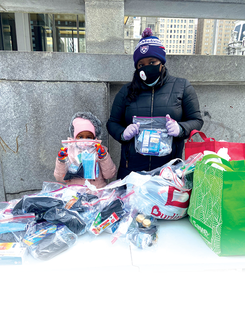 Photo of Kelli Davis and her daughter handing out necessary toiletries, sanitary supplies, clothing, and food to the homeless