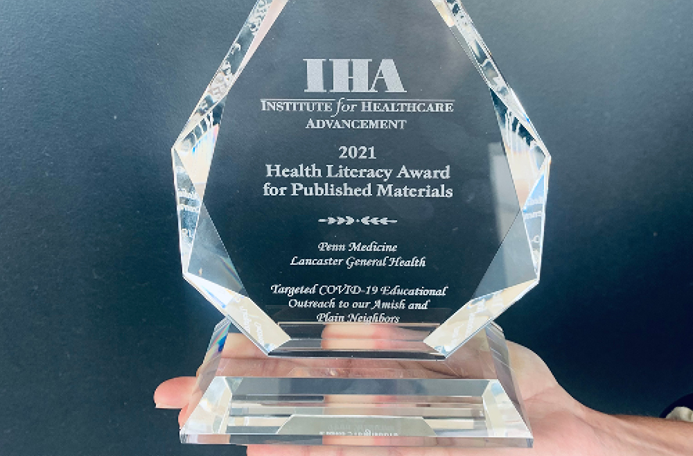 Closeup image of a hand holding the 2021 Health Literacy Award for Published Materials