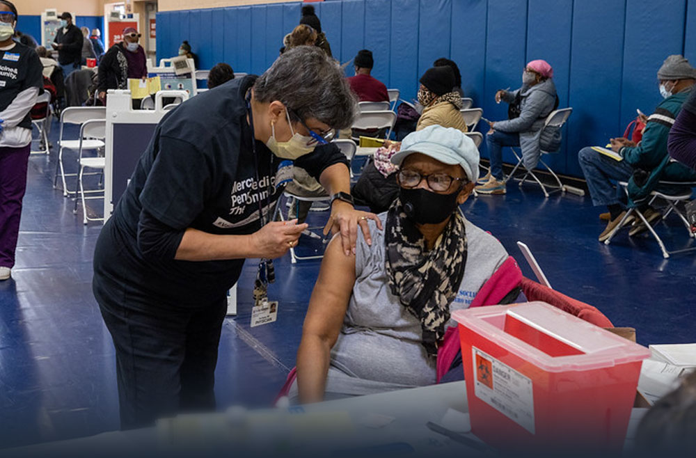 Iris Reyes, MD administering a vaccine to a patient in West Philadelphia