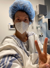 Ginger Mimmo Rohlfing trong áo choàng phẫu thuật và mũ chà trong phòng bệnh nhân.
