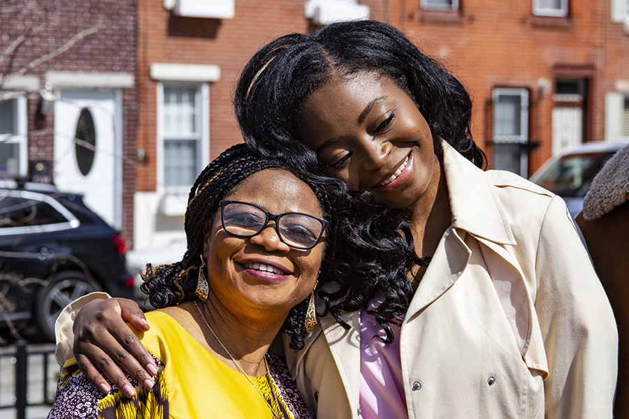 Mariam Olujide, a 2021 graduate of the Perelman School of Medicine, embraces her mother, as both women smile with their eyes closed.
