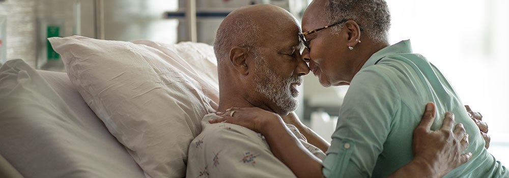 Man in hospital bed hugging woman